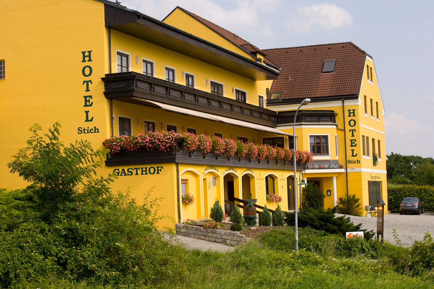 Gelbes Hotelgebäude mit Blumen auf dem Balkon.