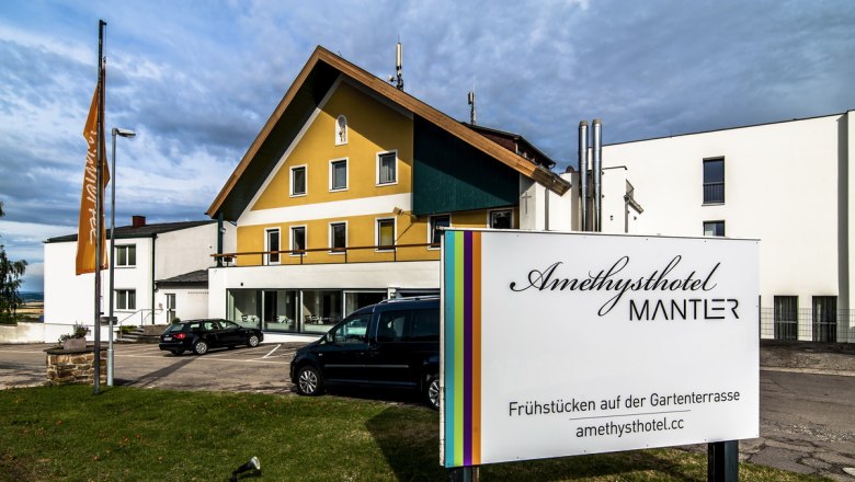 Außenansicht des Amethysthotels Mantler mit Parkplatz und Schild.