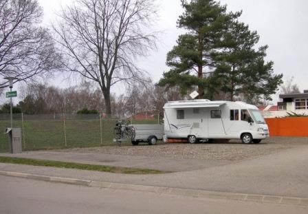 Motorhome on a pitch next to a tree and a fence.