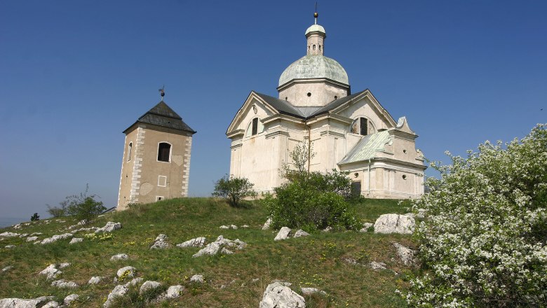 Kapelle auf einem Hügel mit blauem Himmel im Hintergrund.