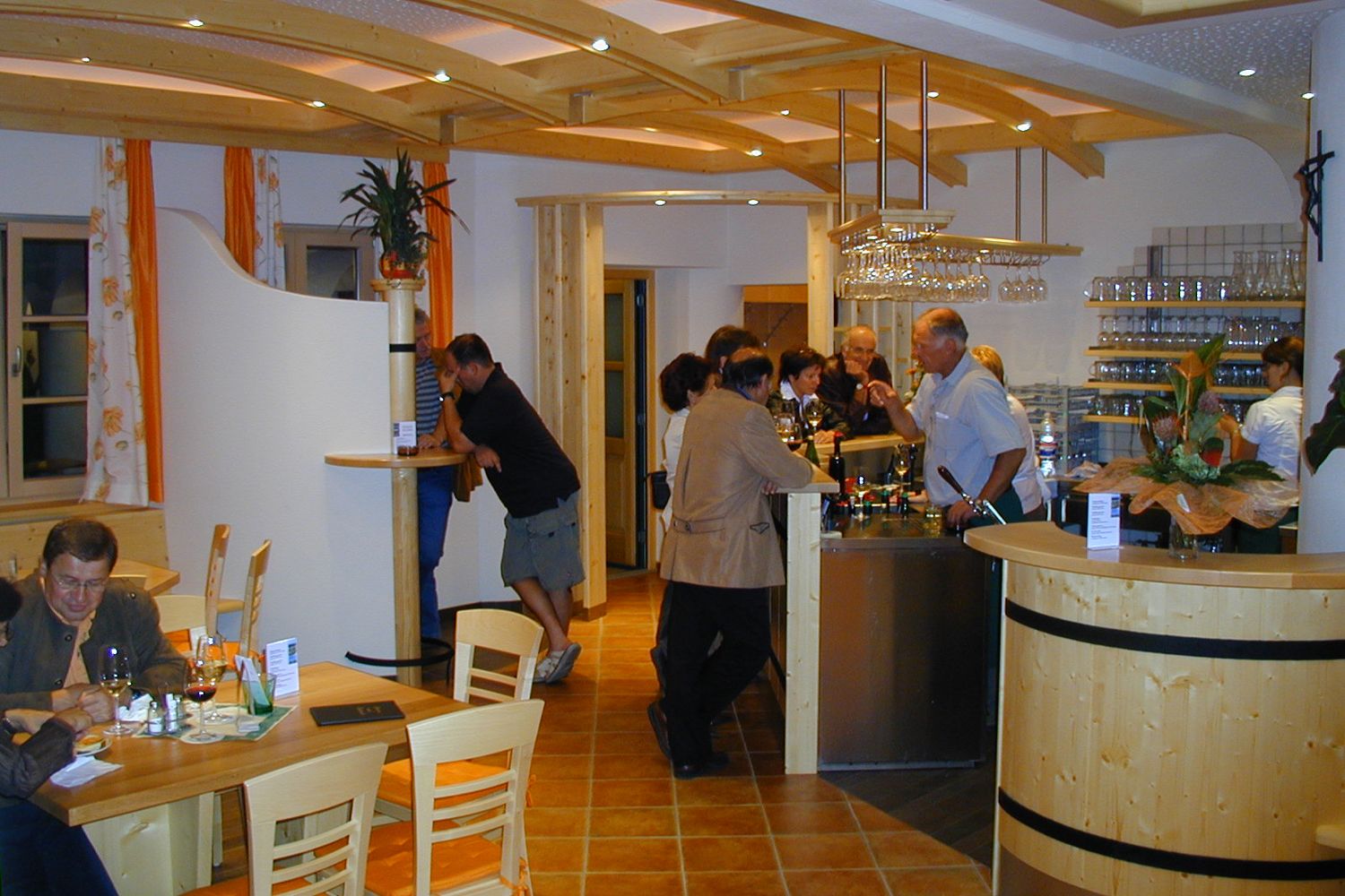 Innenansicht eines Heurigenlokals mit Gästen an der Bar und an Tischen.