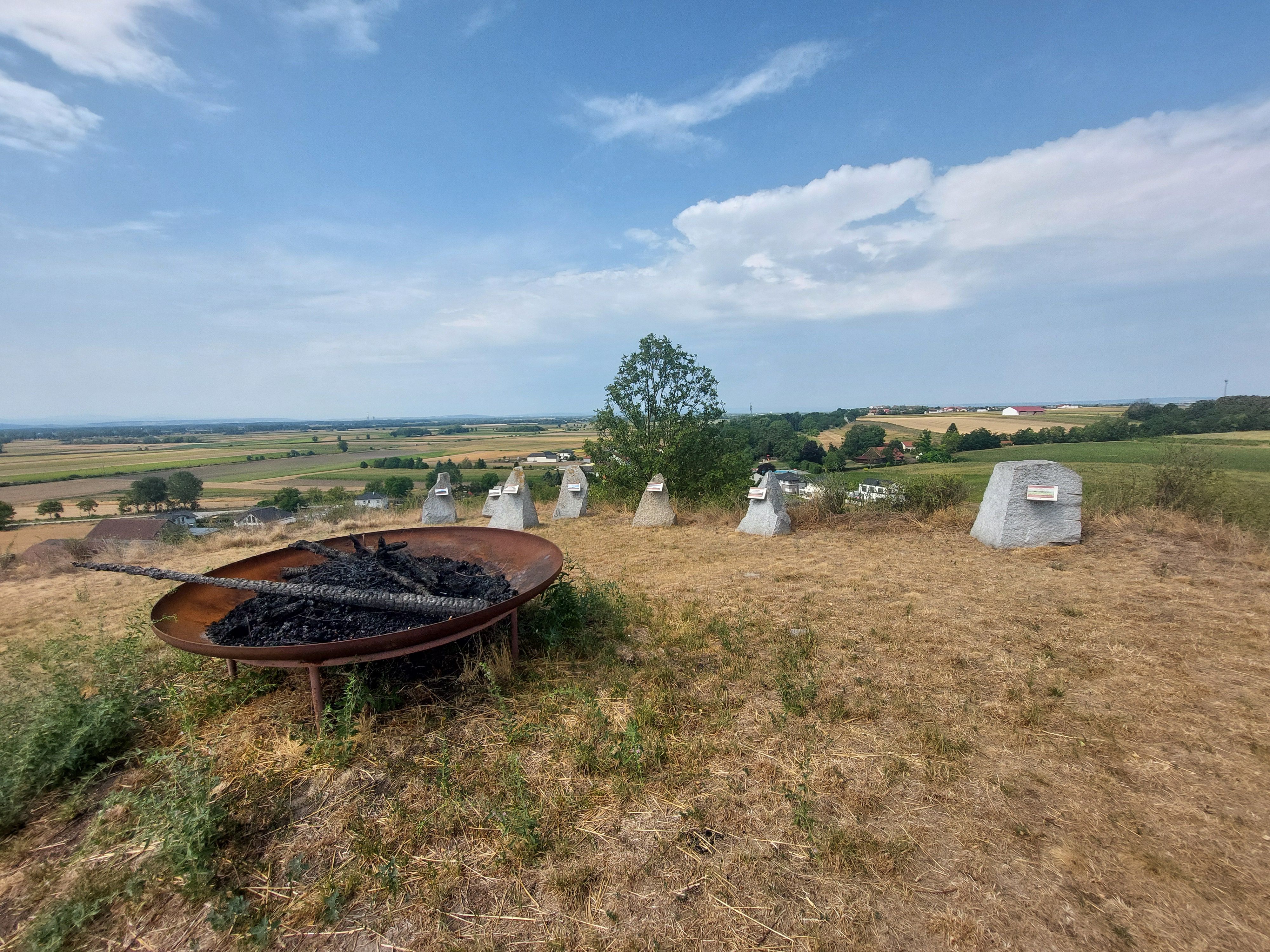Panoramatický výhľad z mohyly Gaisruck s ohniskom v popredí a poľami v pozadí.
