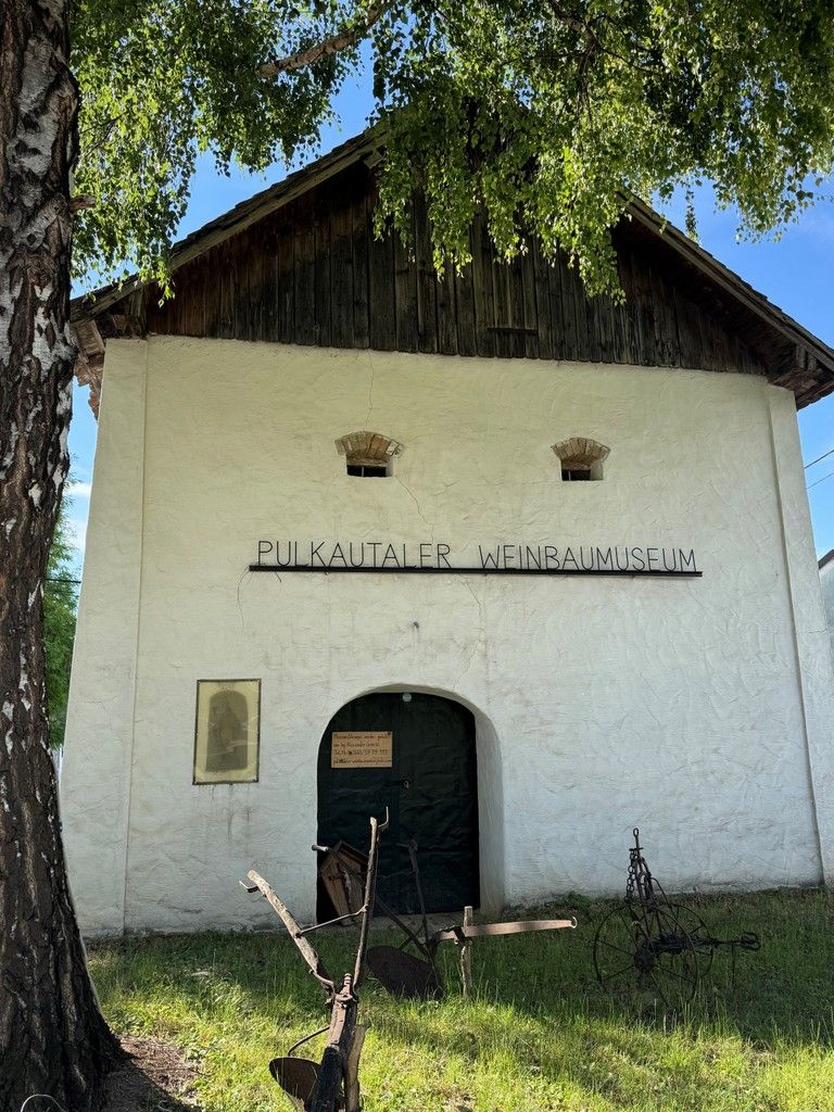 Eingang des Pulkautaler Weinbaumuseums mit alten landwirtschaftlichen Geräten davor.