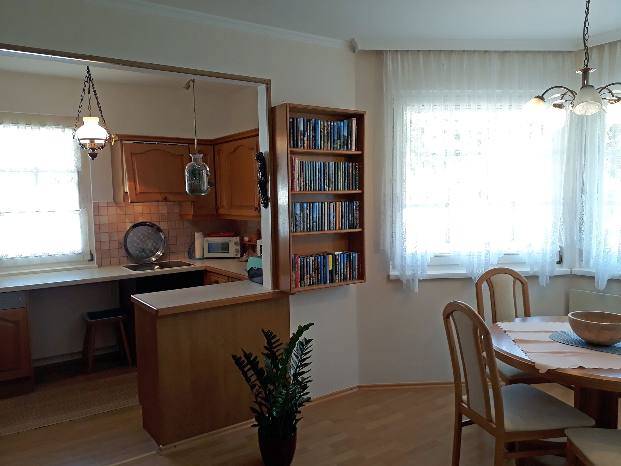 Gemütliche Küche mit Holzmöbeln, Esstisch und Bücherregal.