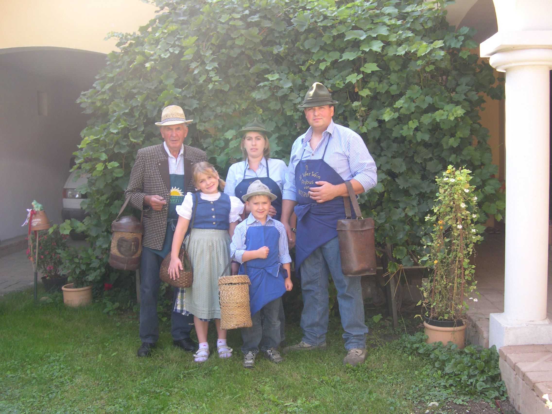 Family in traditional dress in front of a vine.