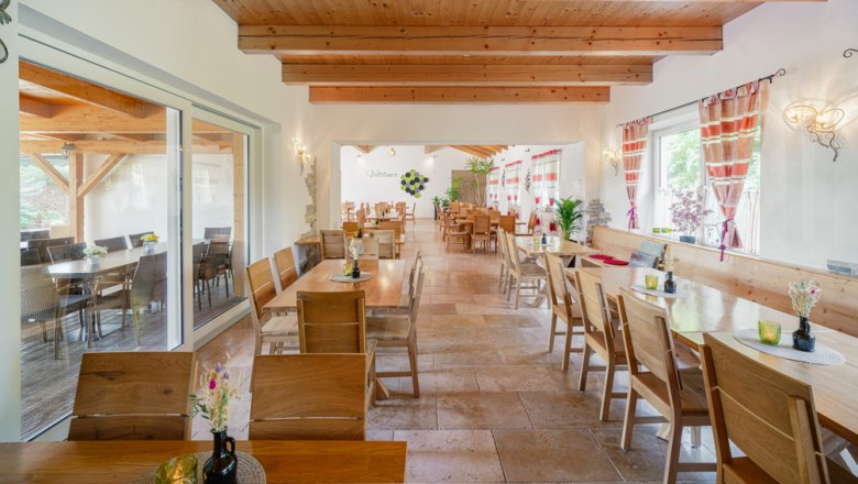 Innenansicht eines gemütlichen Heurigenlokals mit Holzmöbeln und dekorativen Vorhängen.