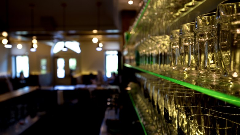 Regal mit Gläsern in einem Restaurant, unscharfer Hintergrund.