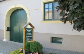 Eingang eines Gästehauses mit grünem Tor und Schild "Haus Resi".