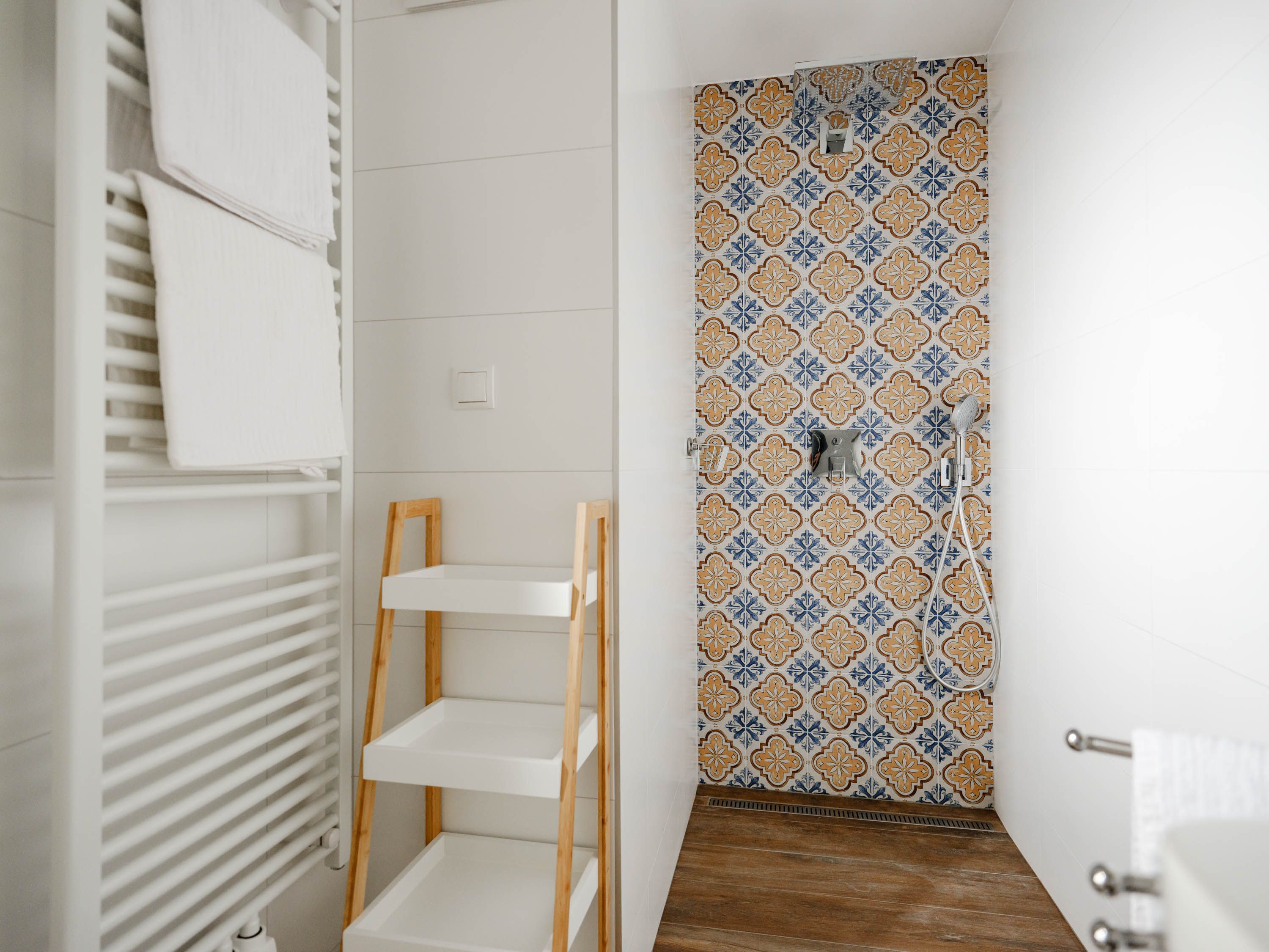 Modernes Badezimmer mit gemusterten Fliesen in der Dusche, Handtuchhalter und Regal.