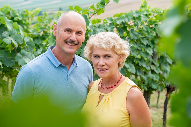 Ein Mann und eine Frau stehen lächelnd in einem Weinberg.