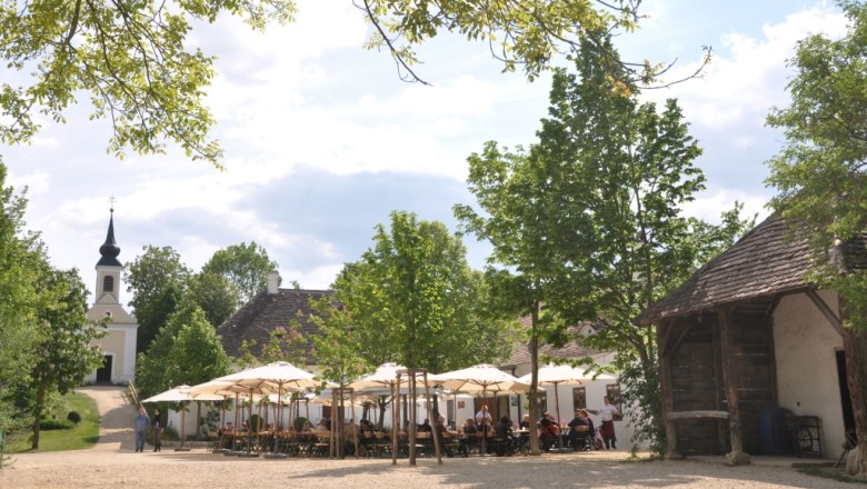 A village inn in the museum village with parasols and a church in the background.