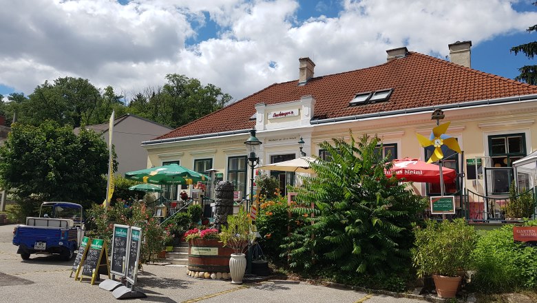 Außenansicht von Buchingers Gasthaus Zur Alten Schule mit Terrasse und Sonnenschirmen.