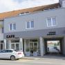 Außenansicht eines grauen Gebäudes mit Café und Gästezimmern.