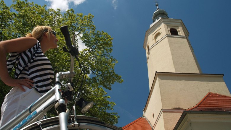 Frau mit Fahrrad vor der Wallfahrtskirche Maria Moos.