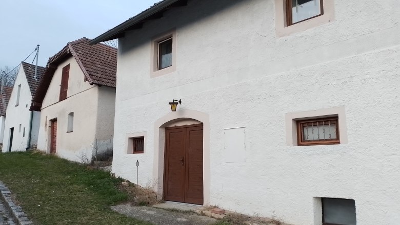 Reihen von weißen Häusern mit braunen Türen und Fenstern, entlang einer Straße mit Grasstreifen.