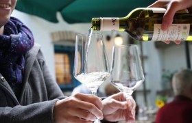 Wein wird in ein Glas gegossen, während eine Person es hält.