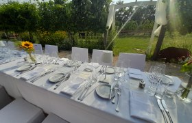 Elegante, gedeckte Tafel im Freien mit weißen Tischdecken und Sonnenblume als Dekoration.