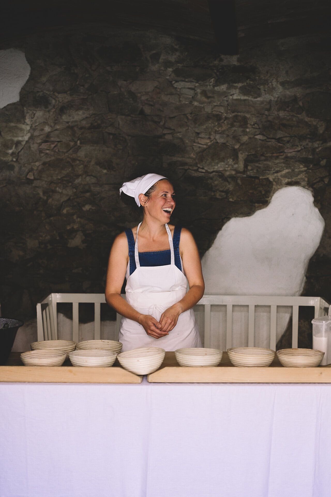 In der malerischen Kulisse der Windmühle Retz strahlt die Freude der Gastgeberin, während sie mit einem Lächeln die köstlichen Speisen präsentiert. Die rustikale Atmosphäre und die einladenden Holzbretter laden dazu ein, die kulinarischen Genüsse der Region zu entdecken und sich von den Aromen des Weinviertels verzaubern zu lassen.