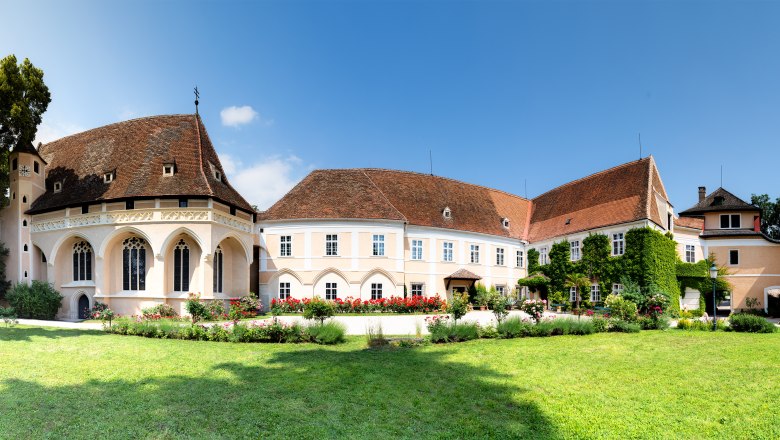 Panoramablick auf das Schloss Schrattenthal mit gepflegtem Garten und bl&uuml;henden Rosen im Vordergrund.