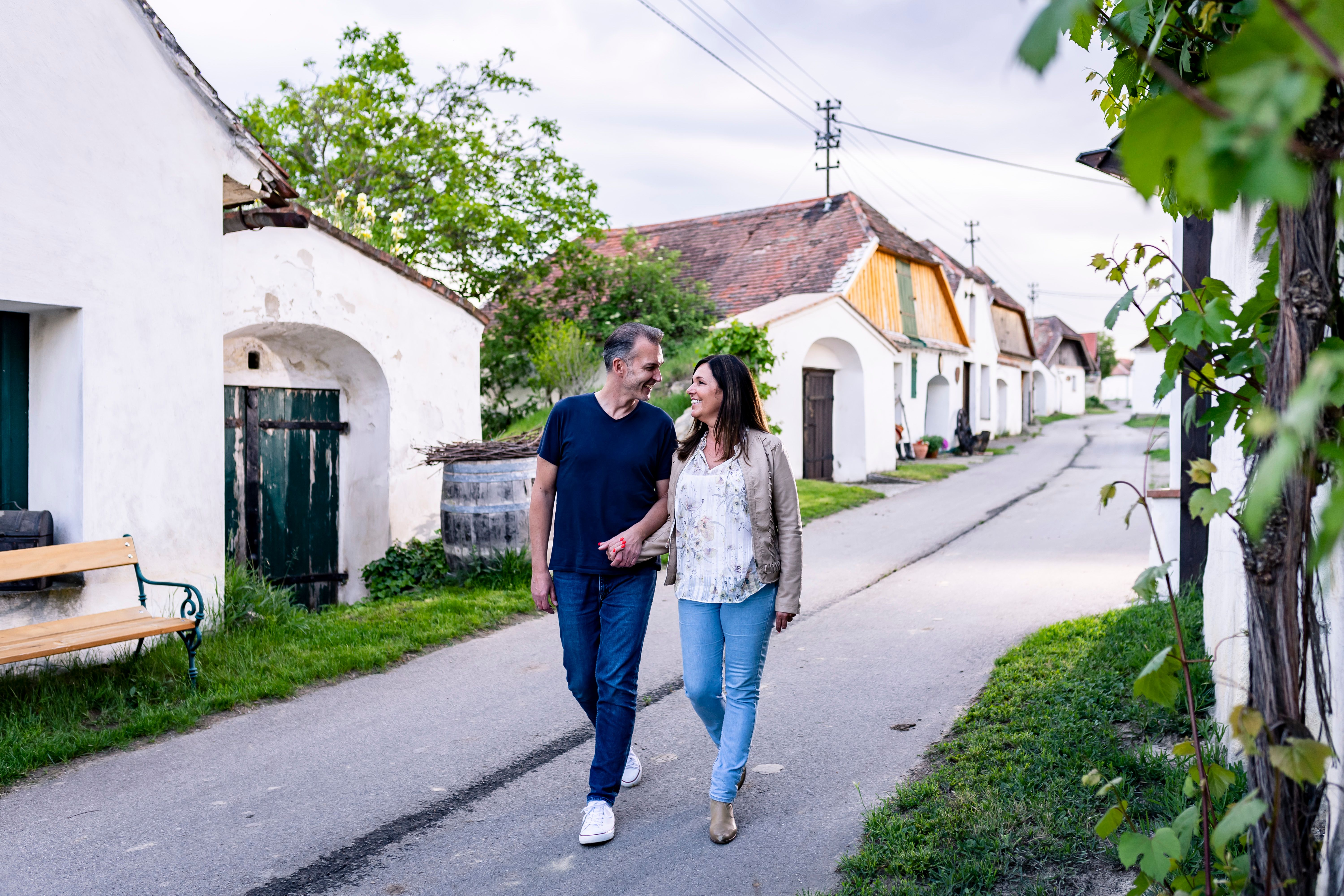 Ein Paar spaziert durch die Kellergasse in Zellerndorf, umgeben von traditionellen Weinkellern.