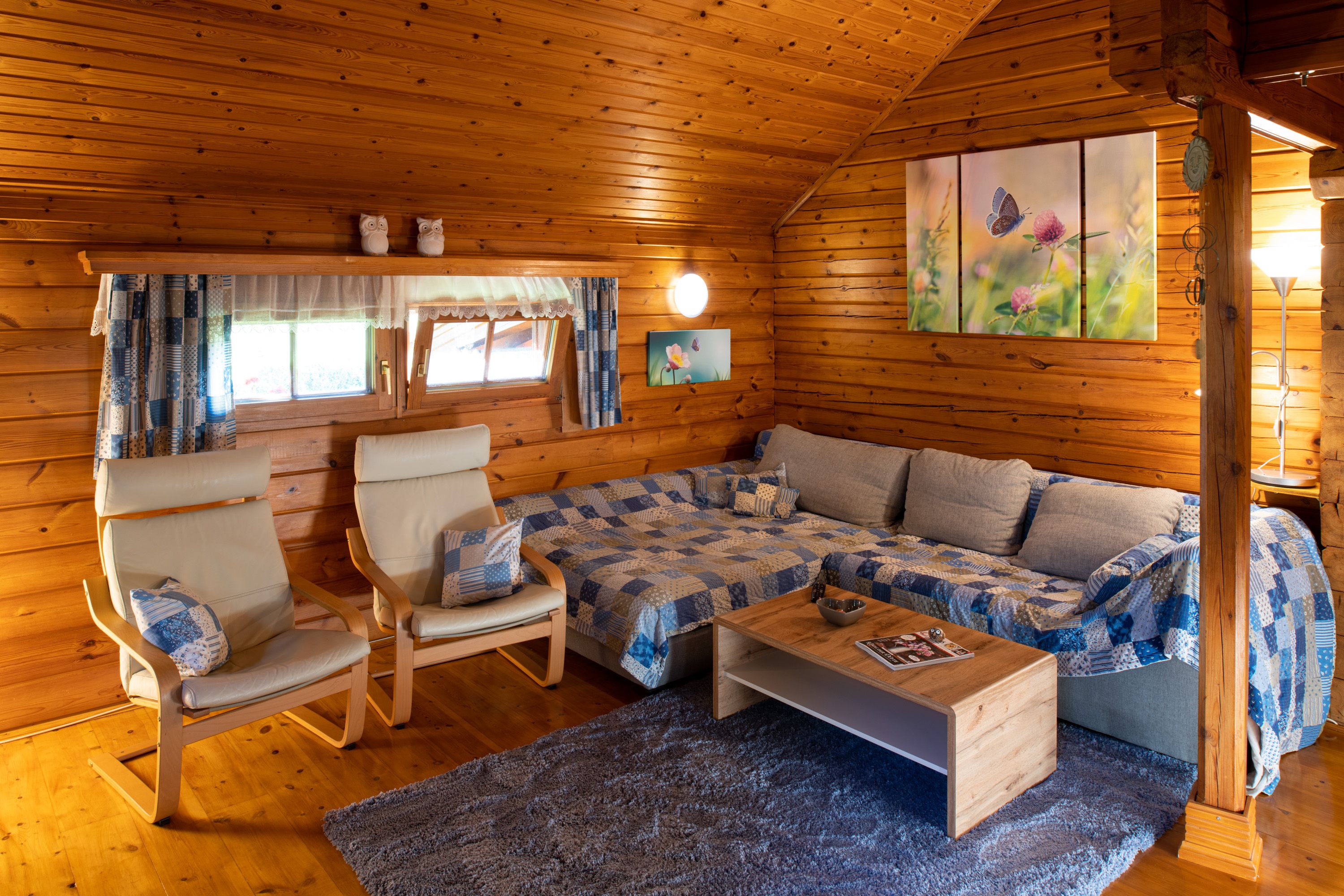 Gemütliches Wohnzimmer in einer Holzhütte mit Sofa, Sesseln und Dekoration.