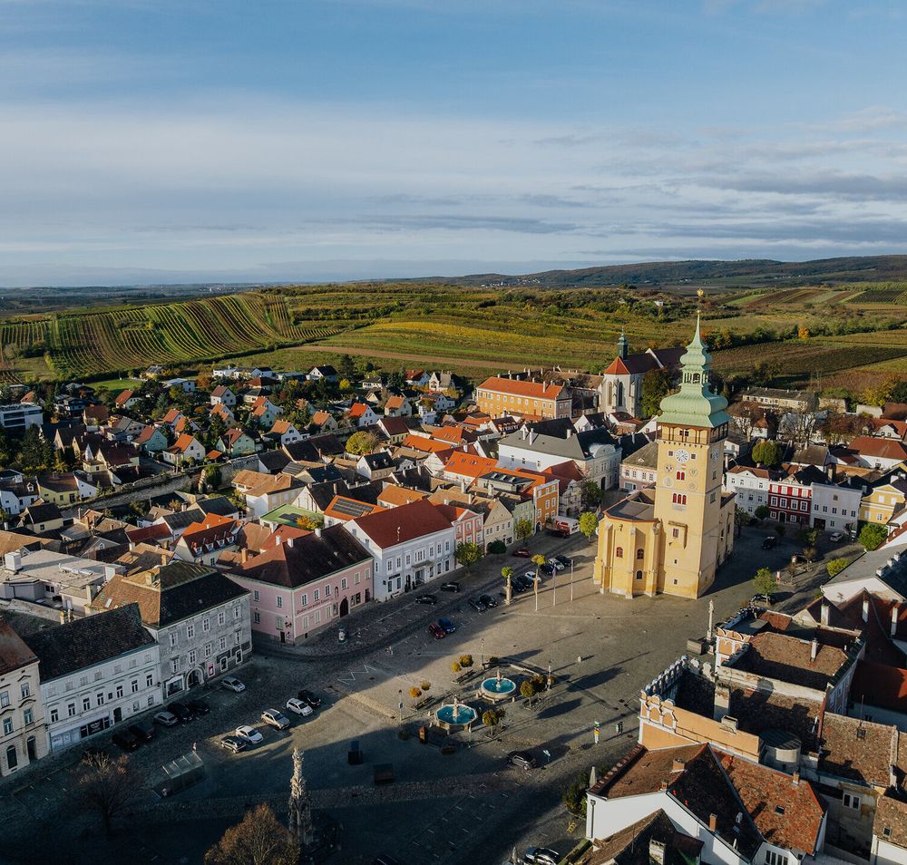 Der Retzer Hauptplatz mit seinen majestätischen Bauten und dem imposanten Rathausturm liegt eingebettet in die herbstliche Weinlandschaft des Retzer Landes.
