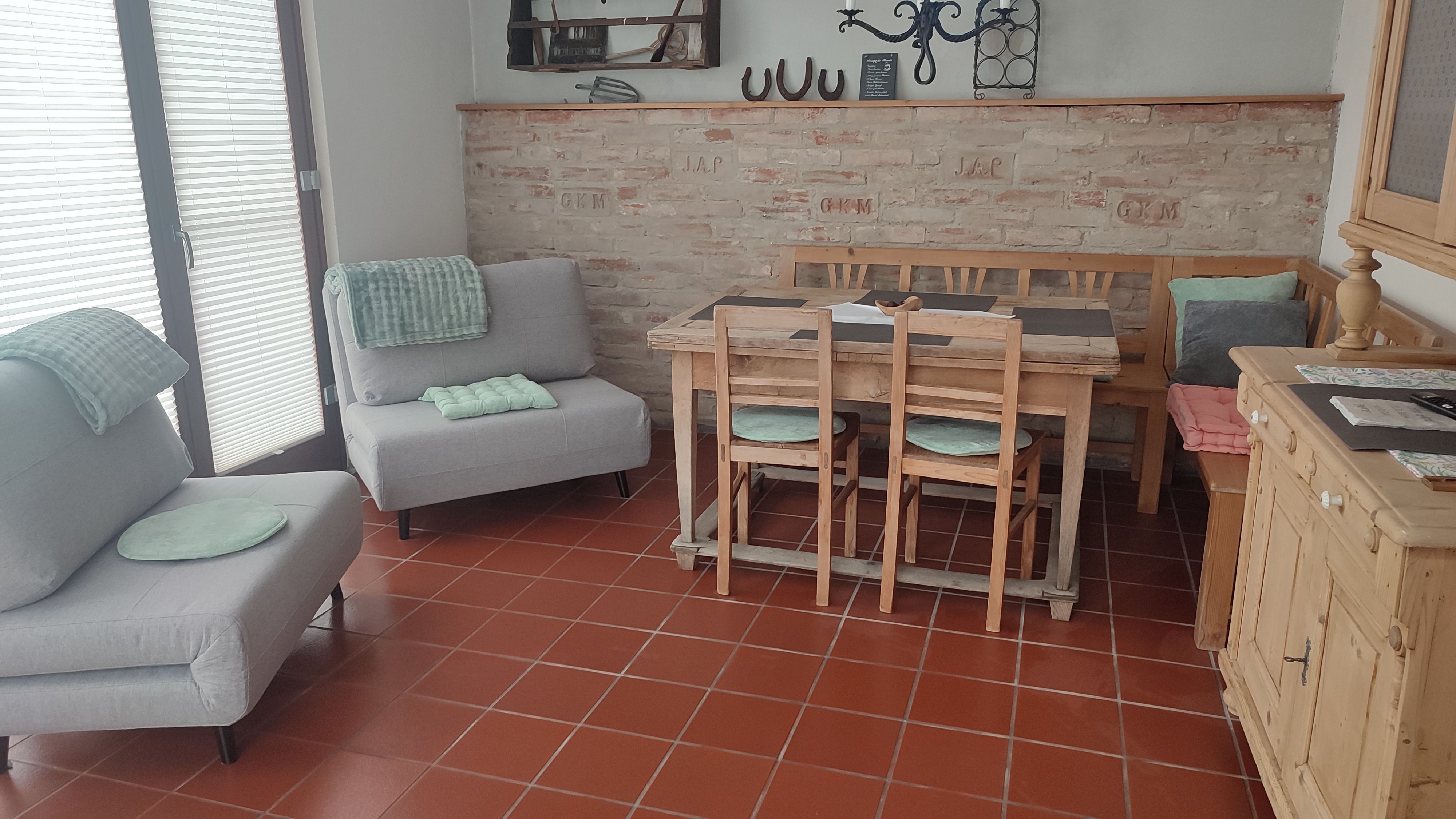 Gemütliches Wohnzimmer mit Holzmöbeln, grauen Sofas und Backsteinwand.