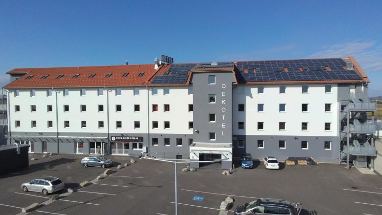 OEKOTEL Föhrenhain mit Solarpanelen auf dem Dach und Parkplatz davor.
