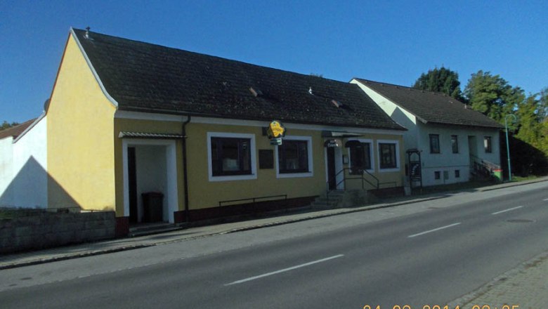 Gelbes Gebäude mit Gasthof-Schild an einer Straße.