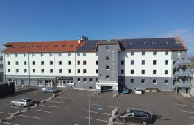 OEKOTEL Föhrenhain mit Solarpanelen auf dem Dach und Parkplatz davor.