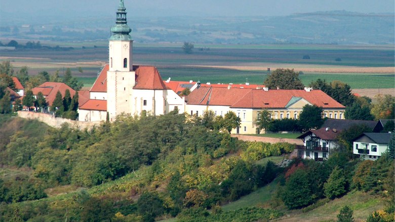 Luftbild der Pfarrkirche St. Agatha auf einem Hügel mit umliegenden Gebäuden und Landschaft.