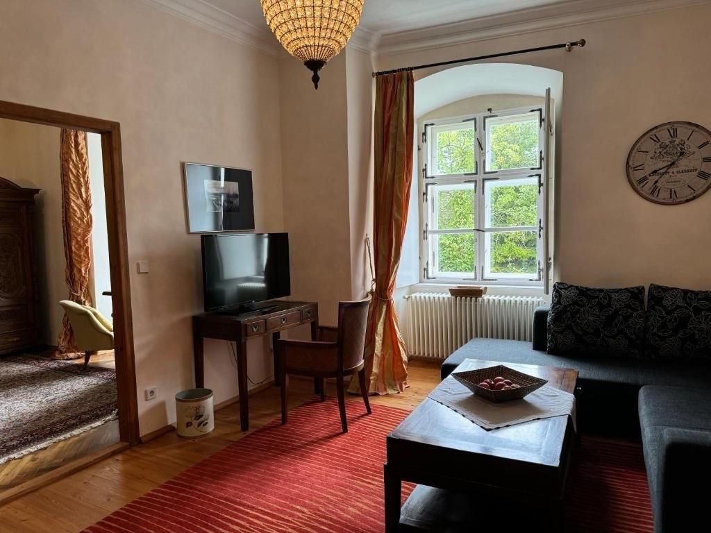 Gemütliches Gästezimmer mit Sofa, Tisch, Fernseher und großem Fenster.