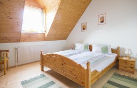 Gem&uuml;tliches Schlafzimmer mit Holzm&ouml;beln und Dachschr&auml;ge.