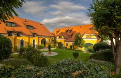 Inmitten der sanften Hügel des Weinviertels entfaltet sich eine malerische Oase, wo die leuchtend gelben Fassaden der Gebäude harmonisch mit dem üppigen Grün des Gartens verschmelzen. Die Atmosphäre ist geprägt von der Ruhe der Natur und dem Duft blühender Pflanzen, die zum Verweilen einladen.
