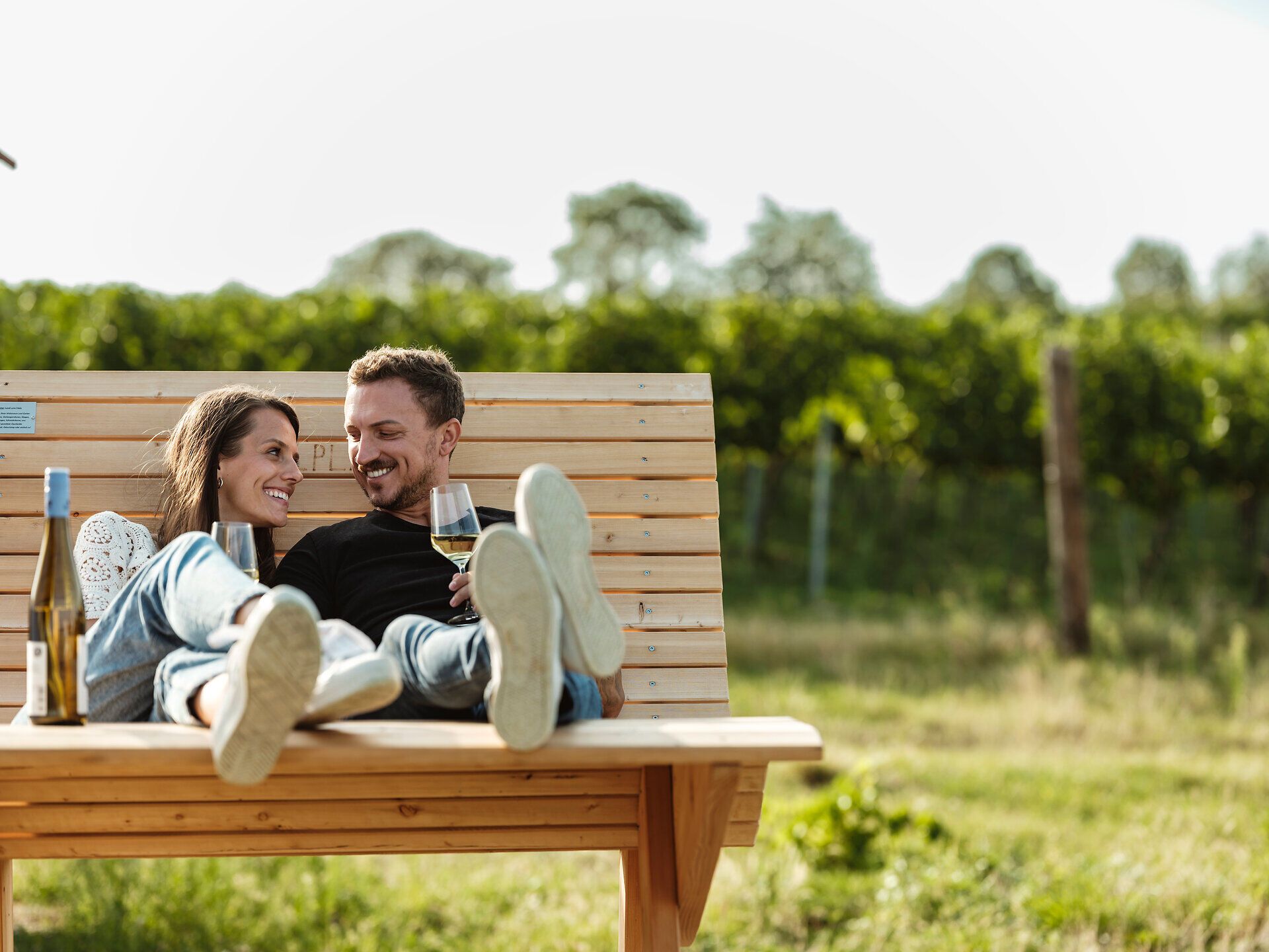 Inmitten der sanften Hügel des Weinviertels genießen ein Paar eine entspannte Auszeit. Umgeben von üppigen Weinreben und der warmen Sonne, teilen sie einen Moment der Zweisamkeit bei einem Glas Wein. Diese idyllische Kulisse lädt dazu ein, die Seele baumeln zu lassen und die Schönheit der Natur zu erleben.