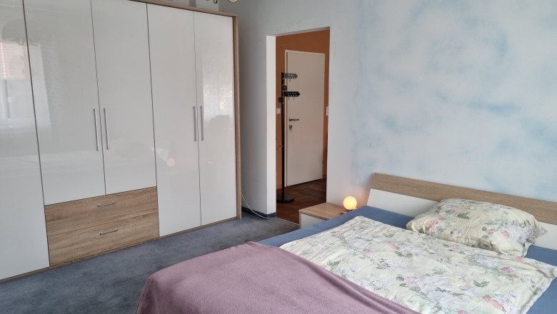 Ein Schlafzimmer mit einem Doppelbett, einem großen weißen Kleiderschrank und einer Nachttischlampe.