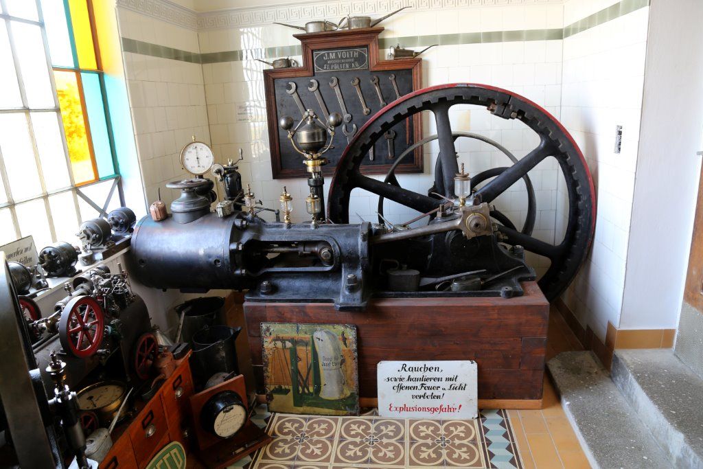 Alte Dampfmaschine im Museum mit Werkzeugen und Warnschild.