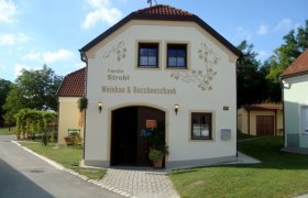 Ein kleines Gebäude mit der Aufschrift 'Familie Strobl Weinbau & Buschenschank'.