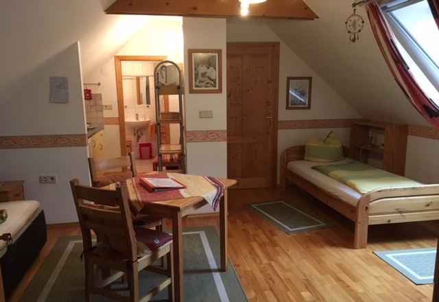 Gemütliche Ferienwohnung mit Holzmöbeln, zwei Betten, Esstisch und Dachfenster.