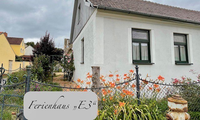 Außenansicht, © Julia Grünschachner Außenansicht eines weißen Ferienhauses mit Garten und Blumen.