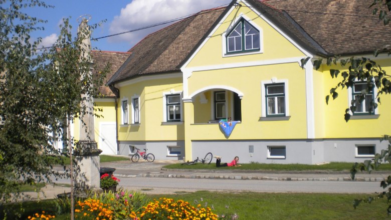 Gelbes Gästehaus mit Blumenbeet und Fahrrädern davor.
