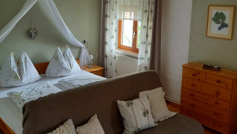 Gem&uuml;tliches G&auml;stezimmer mit Doppelbett, Sofa und Holzm&ouml;beln.