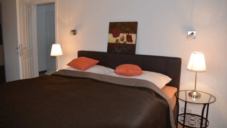 Schlafzimmer mit Doppelbett, zwei Nachttischlampen und einem Gemälde an der Wand.