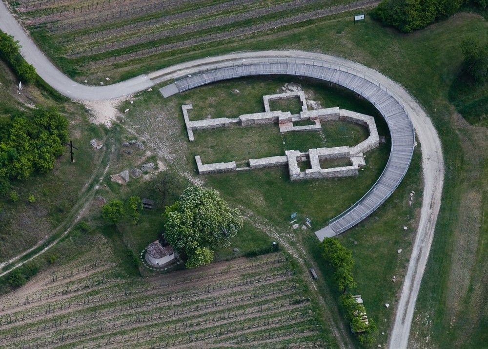Aerial view of an archaeological excavation site with a semi-circular footbridge.