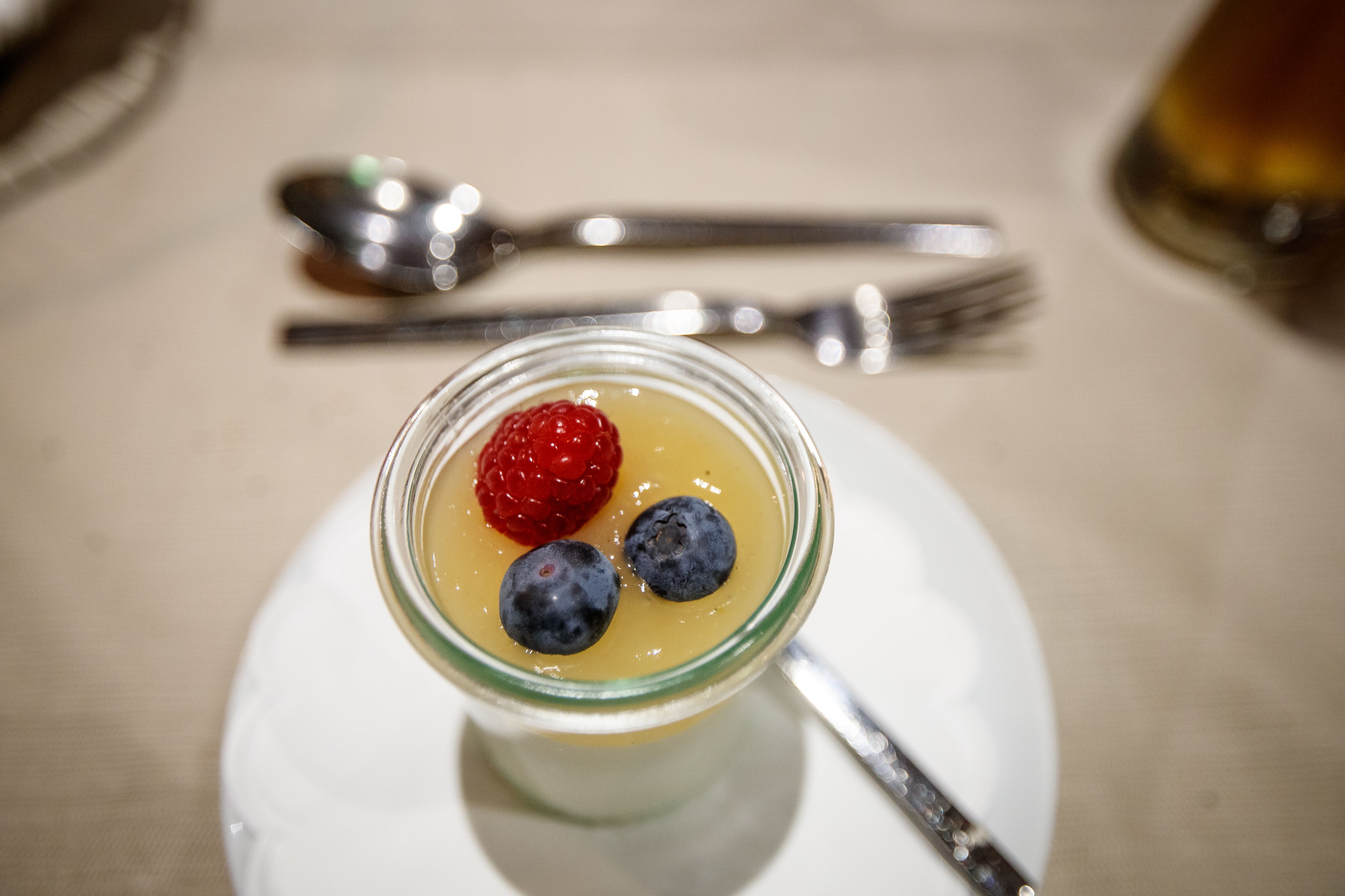 Dessert im Glas mit Himbeere und Blaubeeren auf einer Tischdecke.