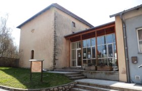 Ein historisches Gebäude mit modernem Anbau und einem Schild im Vordergrund.