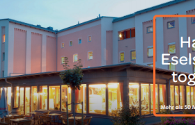 Außenansicht des JUFA Hotels bei Abenddämmerung mit HolidayCheck Award 2016 Logo.