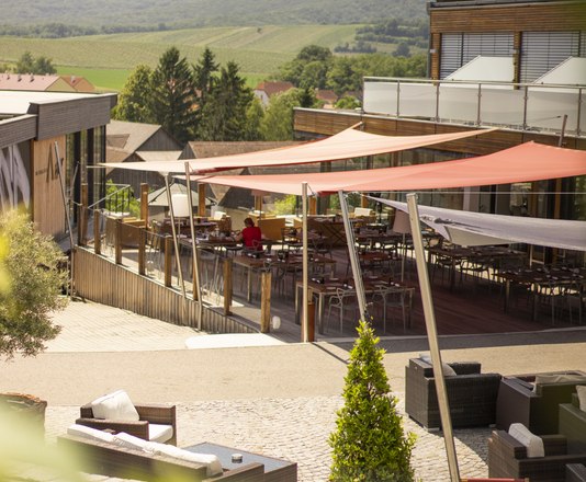 Terrace with awnings and seating, surrounded by green countryside.