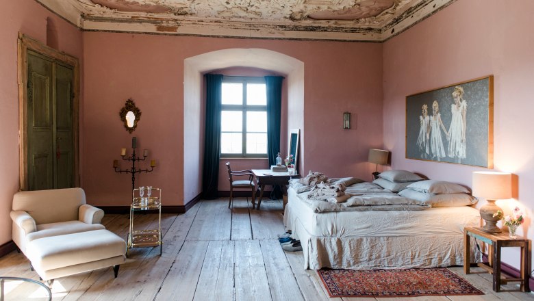 Elegantes Schlafzimmer mit antiker Decke, rosa Wänden und Holzboden.