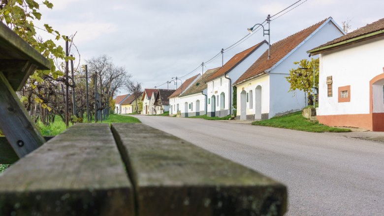 Wine cellar lane in Niederschleinz with wine cellars and a bench in the foreground.